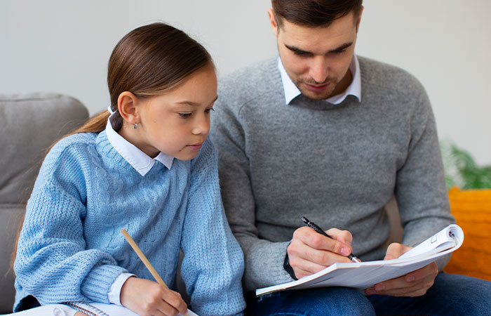 padre-e-hija-haciendo-deberes Padre e hija haciendo los deberes en el sofá